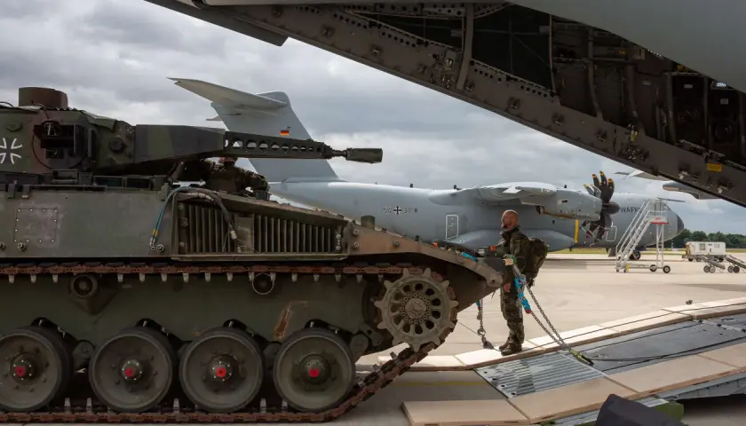 Ein Soldat sichert einen Panzer, der für den Transport in ein großes Flugzeug vorbereitet wird.