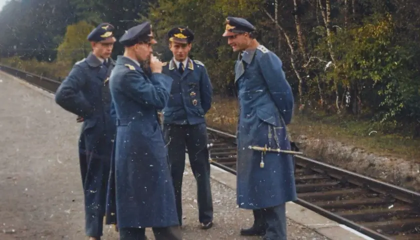 Vier Männer in blauen Uniformen, einige mit Portepee, stehen am Bahnsteig.