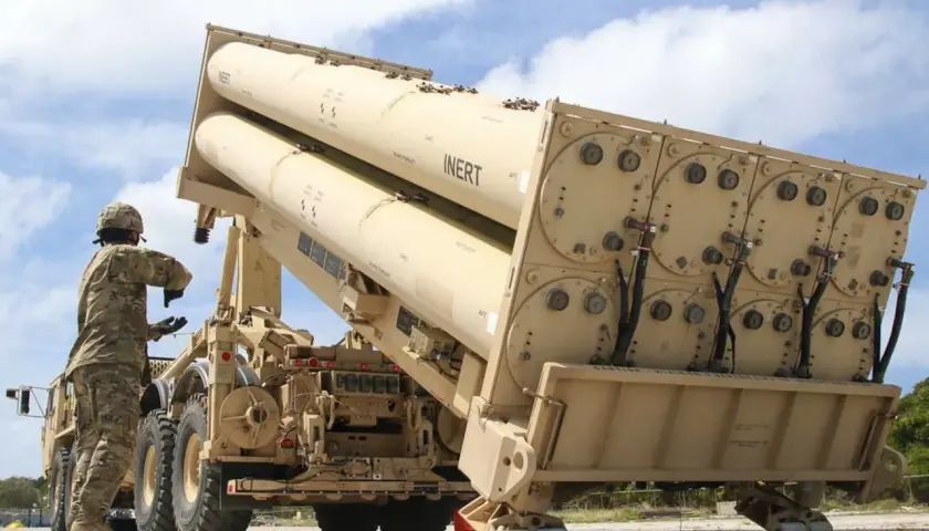 Soldat lädt Raketen für das THAAD-System. Große, beige Raketen sind auf einem LKW montiert, bereit für den Einsatz.