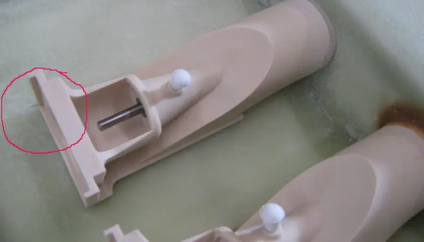 Zwei Teile eines wellenantrieb d-drive Systems, beige, mit Metallachsen und weißen Kugeln, liegen in einer grünen Flüssigkeit.