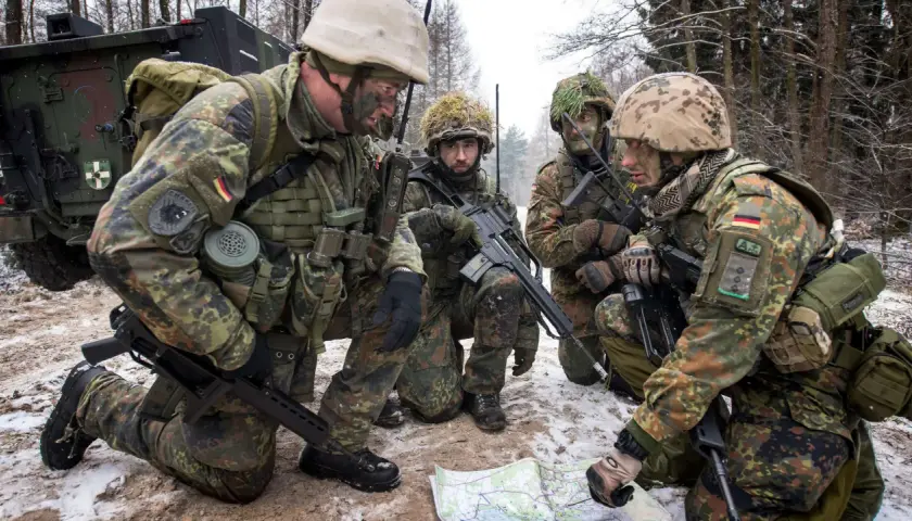 Soldaten der Bundeswehr im Wald, ein Leutnant deutet auf eine Karte.