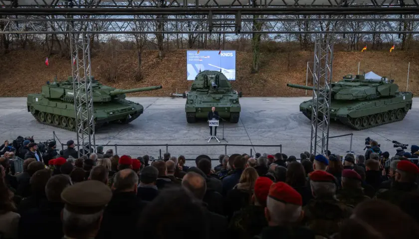 Drei Panzer, ein Redner und eine Zuschauermenge bei einer Veranstaltung.