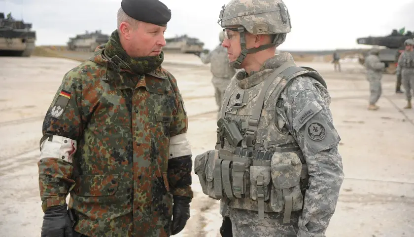 Zwei Soldaten im Gespräch, einer mit deutschem Tarnmuster und schwarzem Barett, der andere in US-Uniform. Der deutsche Soldat trägt den oberstleutnant dienstgrad.