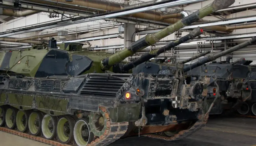 Mehrere Leopard 1 Panzer stehen in einer Halle. Ihre Kanonen ragen nach oben.