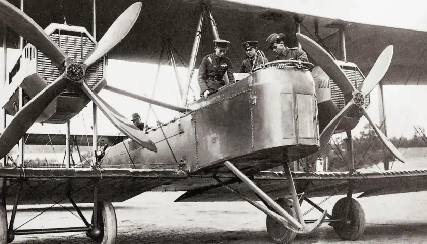 Männer in Uniformen stehen auf einem historischen hochdecker flugzeug.