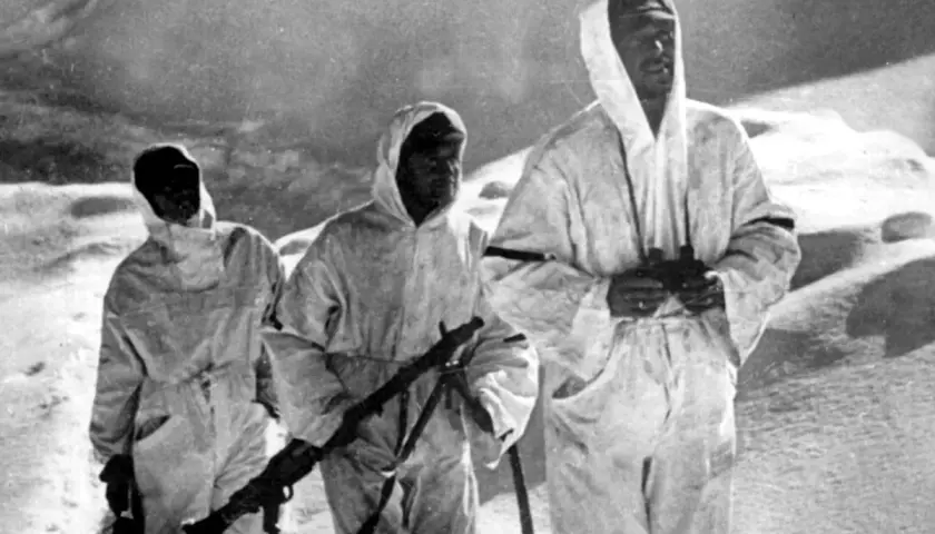Drei Soldaten der Wehrmacht in Wintertarnung auf dem Elbrus, einer mit Fernglas, ein anderer mit Gewehr.