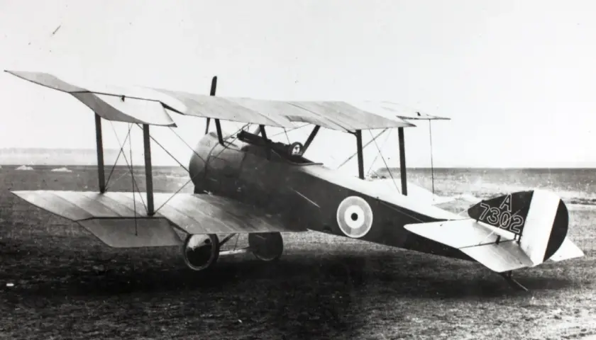 Ein Sopwith Pup Doppeldeckerflugzeug mit der Kennung A 7302 steht auf einem Feld.
