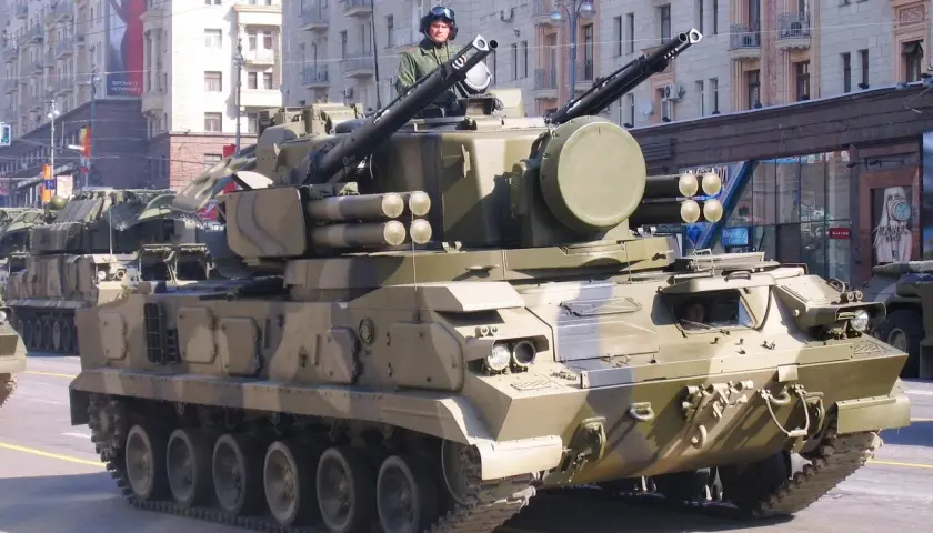 Ein 2K22 Tunguska Flugabwehrpanzer fährt in einer Parade. Der Soldat im Turm trägt einen Helm und eine Uniform.