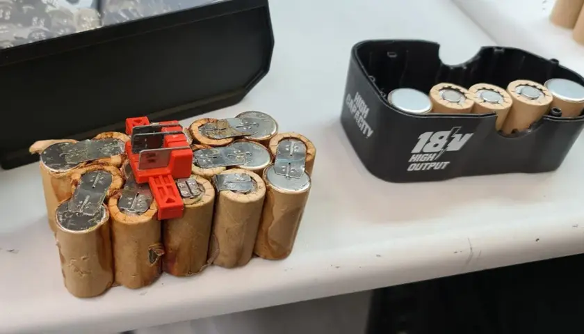 Ein defekter NiCd Akku, bereit für das Nicd Akku wiederbeleben. Daneben ein 18V Akku-Gehäuse.
