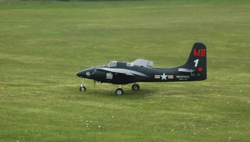 Ein schwarzes Modellflugzeug, ein f7f Tigercat, steht auf einem grünen Feld.