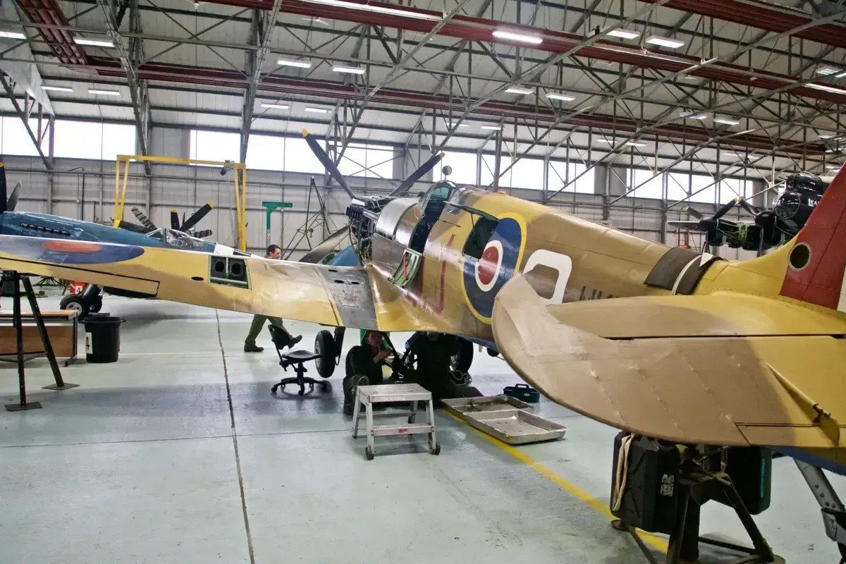 Flugzeugmuseum Usedom: Techniker arbeiten an einem historischen Jagdflugzeug in einer Werkstatthalle.