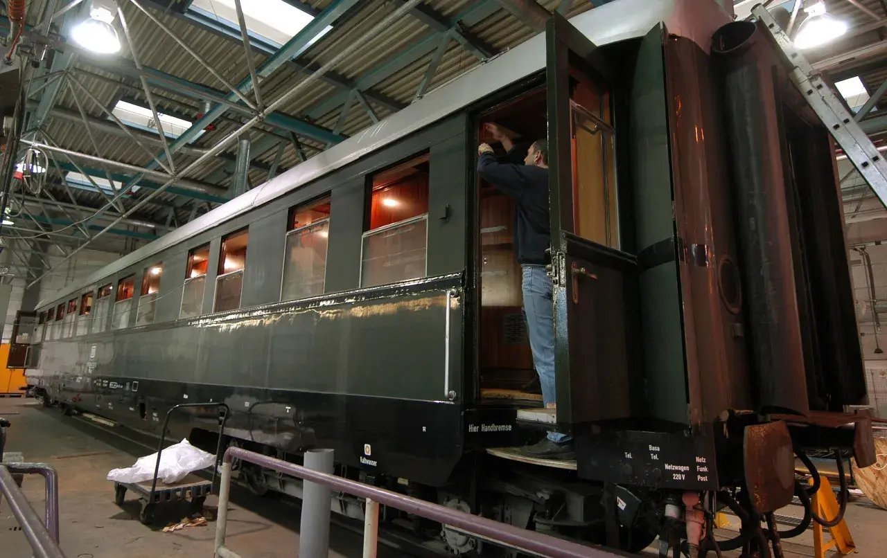 Ein Mann arbeitet an einem historischen Zugwaggon, der an Hitlers Panzerzug erinnert.