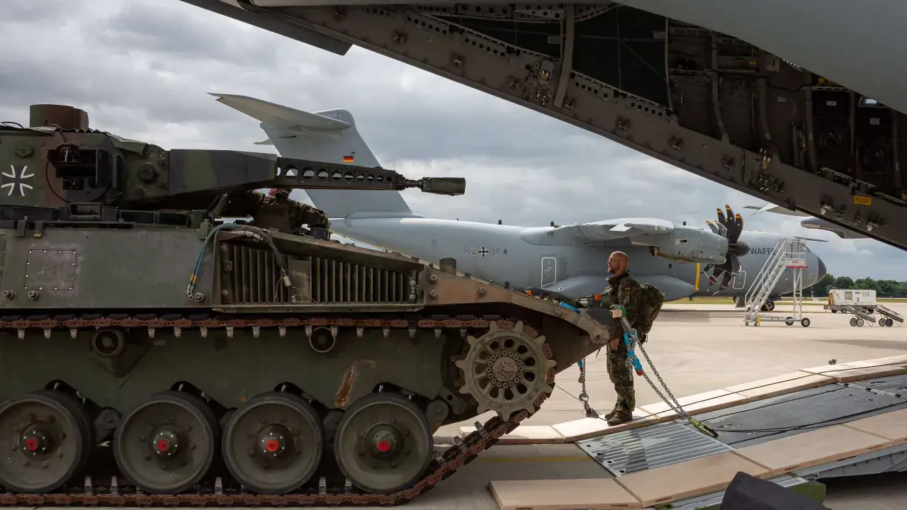 Ein Soldat sichert einen Panzer, der für den Transport in ein großes Flugzeug vorbereitet wird.