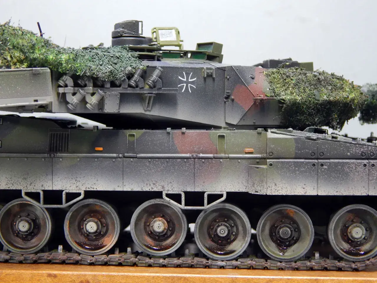 Detailaufnahme eines deutschen Panzers im Tarnmuster mit Tarnnetz. Das Modell zeigt die charakteristischen Räder und Ketten.