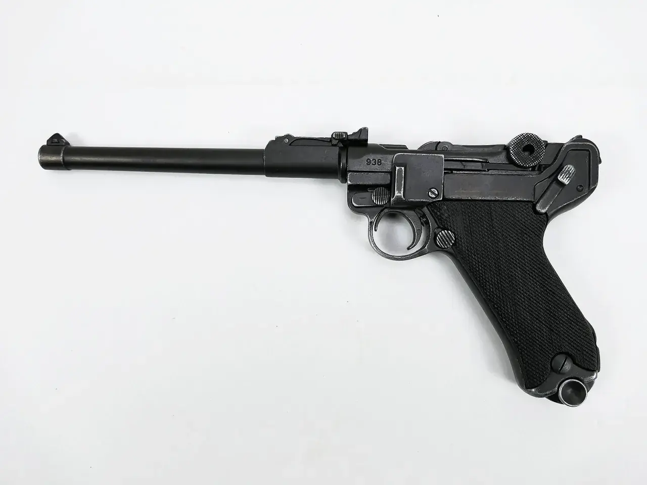 Eine schwarze Luger Pistole mit nummeriertem Schlitten (938) und geriffeltem Griff liegt auf weißem Grund.