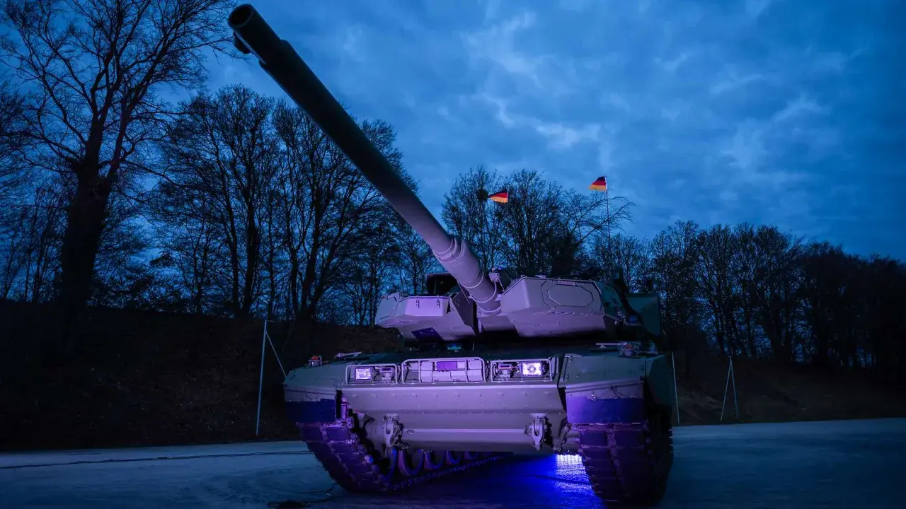 Ein moderner Leopard 2 panzer steht im Dunkeln, beleuchtet von blauem Licht. Deutsche Flaggen wehen im Hintergrund.