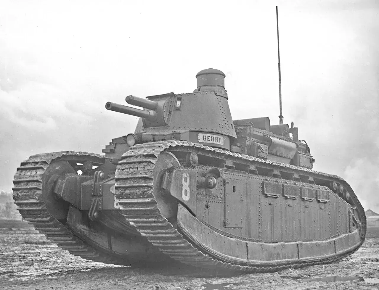 Ein schwerer Panzer, Modell char 2c, mit zwei Kanonen und dem Namen "Berry" auf dem Turm, steht auf schlammigem Gelände.