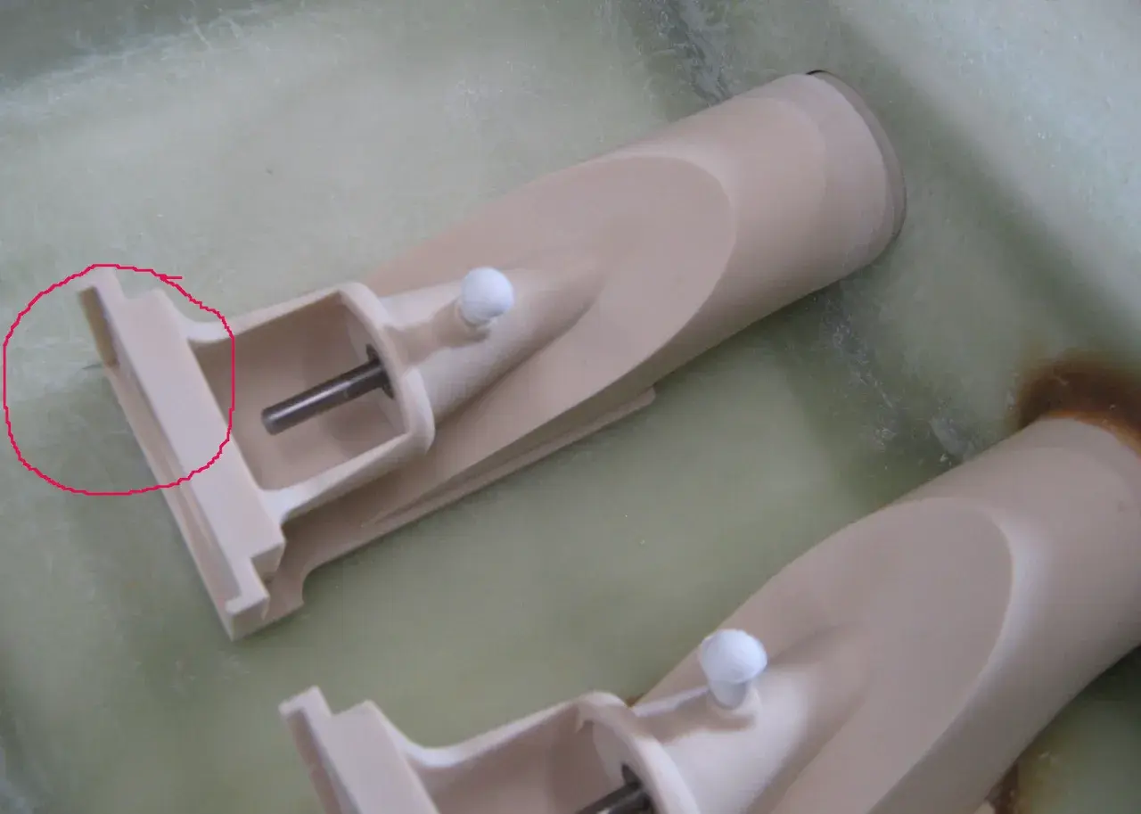 Zwei Teile eines wellenantrieb d-drive Systems, beige, mit Metallachsen und weißen Kugeln, liegen in einer grünen Flüssigkeit.