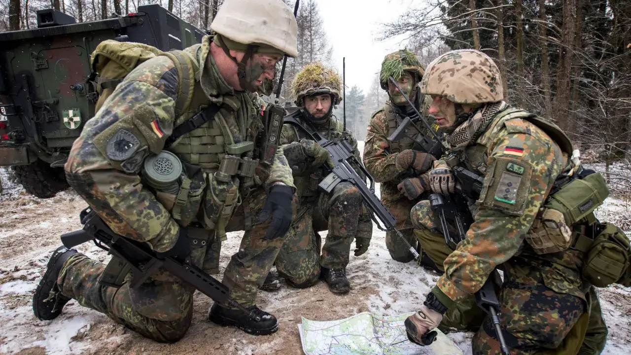 Soldaten der Bundeswehr im Wald, ein Leutnant deutet auf eine Karte.