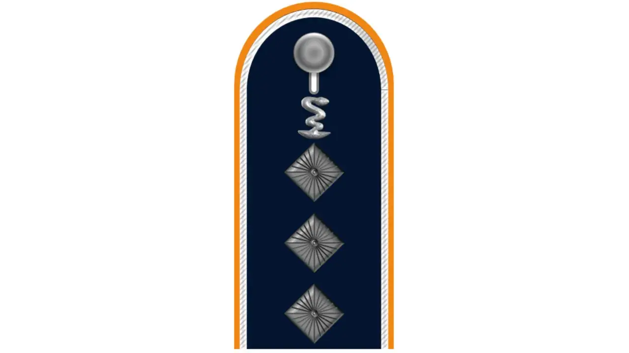 Dunkelblaues Kragenabzeichen mit silbernem Stab und Schlange, drei Rauten. Ein Feldwebel der Bundeswehr trägt dieses Abzeichen.