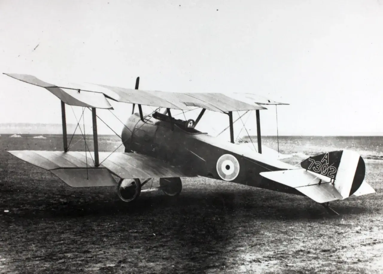 Ein Sopwith Pup Doppeldeckerflugzeug mit der Kennung A 7302 steht auf einem Feld.