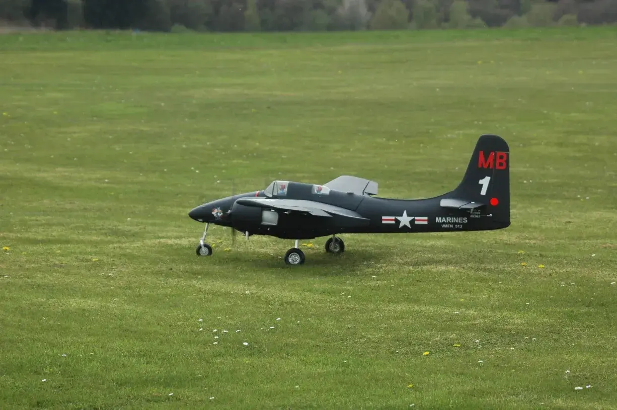 Ein schwarzes Modellflugzeug, ein f7f Tigercat, steht auf einem grünen Feld.