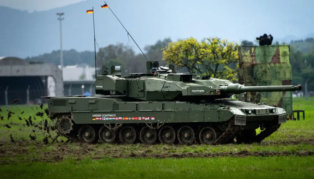 Ein Leopard 2 Panzer fährt durch matschiges Gelände. Die Frage