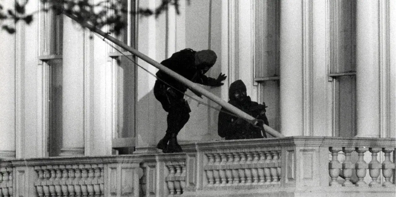 Zwei maskierte Männer, Teil der Operation Nimrod, bewegen sich vorsichtig über eine Balustrade.