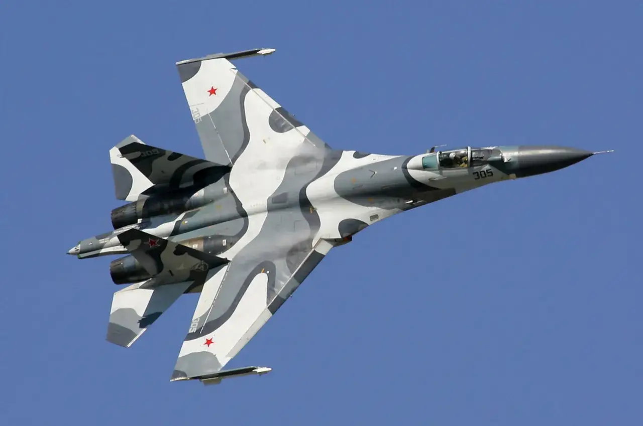 Suchoi Su-27 im Tarnmuster fliegt gegen blauen Himmel.