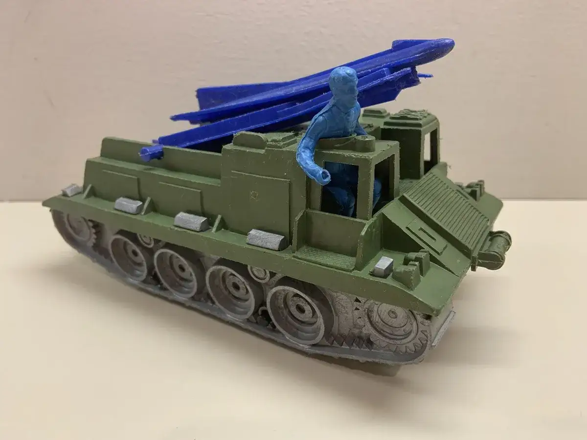 Grüner Spielzeug-Raketenwerfer-Panzer mit blauer Figur und Raketen.