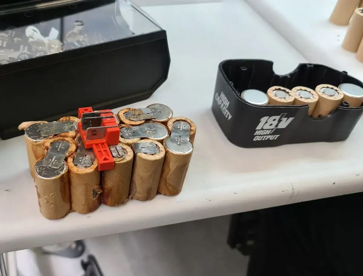 Ein defekter NiCd Akku, bereit für das Nicd Akku wiederbeleben. Daneben ein 18V Akku-Gehäuse.