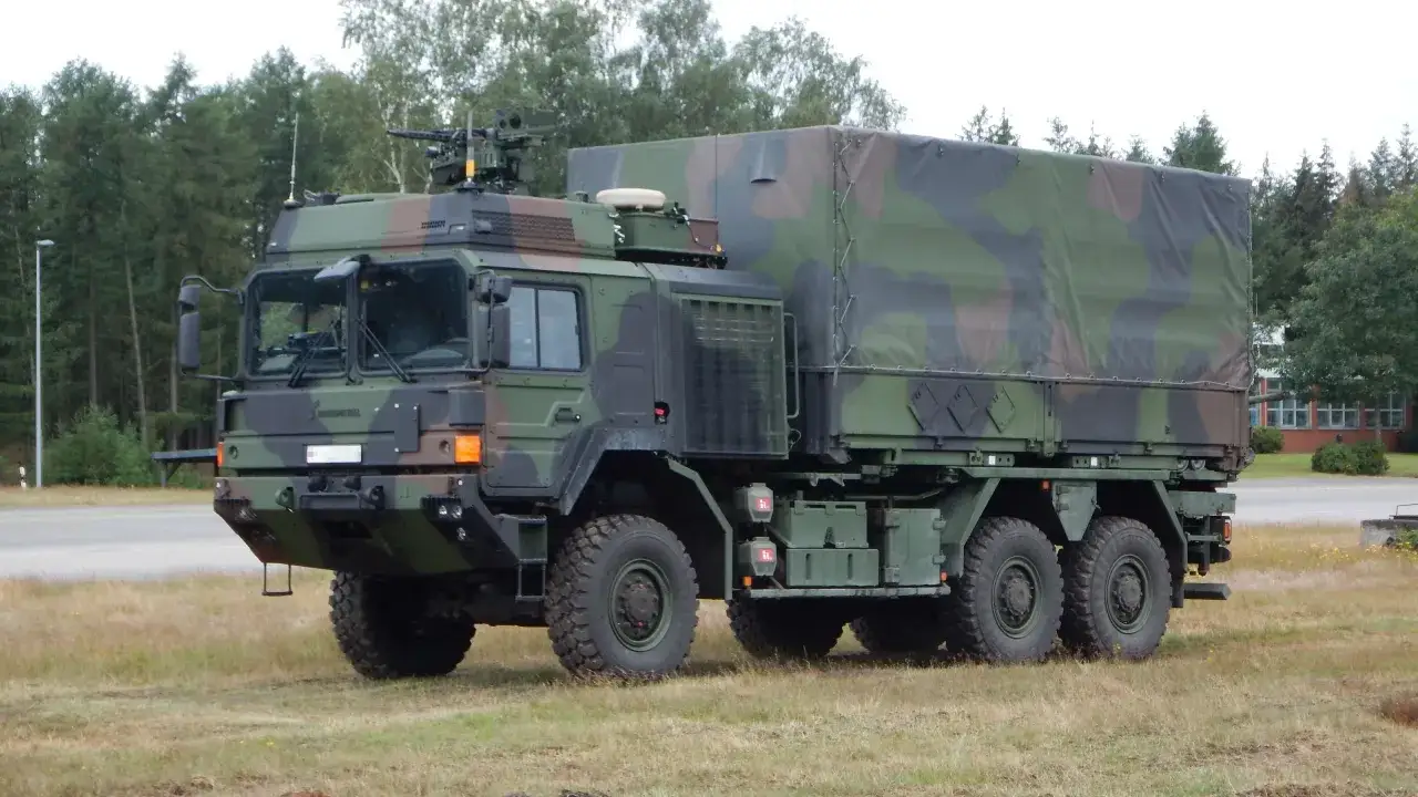 Ein gepanzerter LKW der Bundeswehr mit Tarnmuster und einer Waffenstation auf dem Dach steht auf einem Feld.