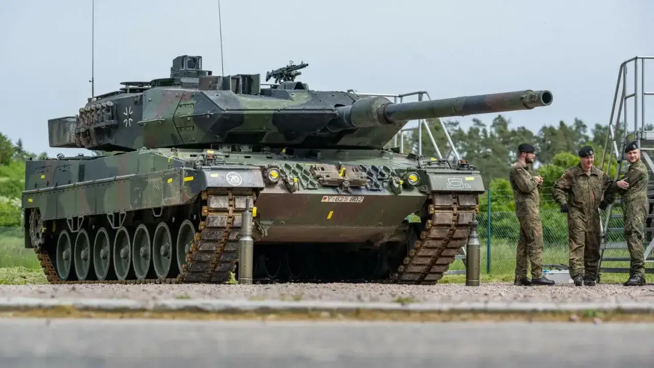 Ein moderner Panzer Leopard 2, der an den Zweiten Weltkrieg erinnert, steht neben Soldaten.