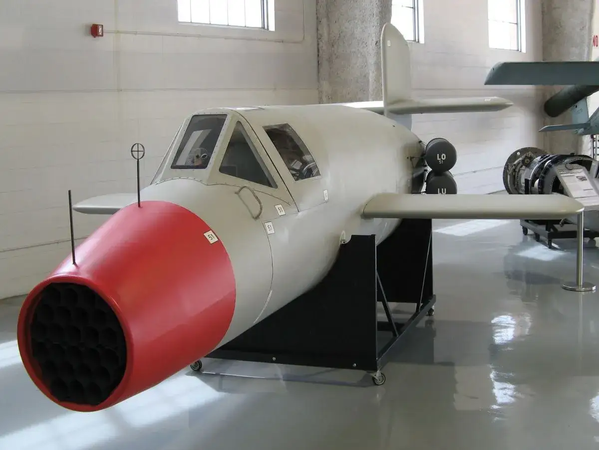 Das Flugzeug Natter, ein Raketenjäger, steht in einem Museum. Sein roter, konischer Bug mit vielen kleinen Öffnungen ist gut sichtbar.