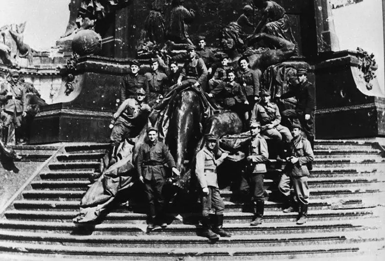 Soldaten der Roten Armee posieren 1945 auf den Stufen eines zerstörten Denkmals vor dem Reichstag.