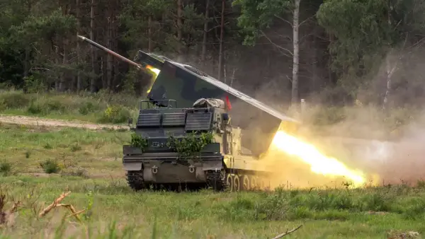 Ein Raketenwerfer auf Panzerbasis feuert eine Rakete ab, begleitet von hellem Feuer und Rauch.